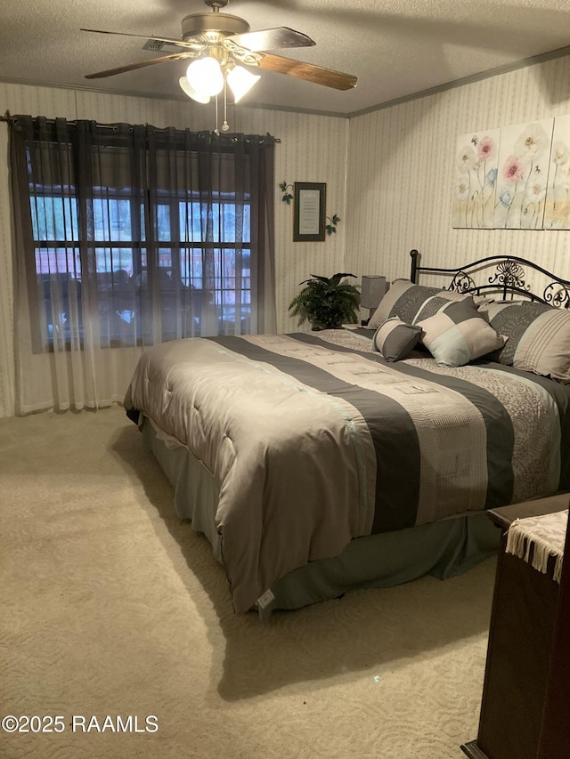 bedroom featuring carpet, ornamental molding, ceiling fan, and a textured ceiling