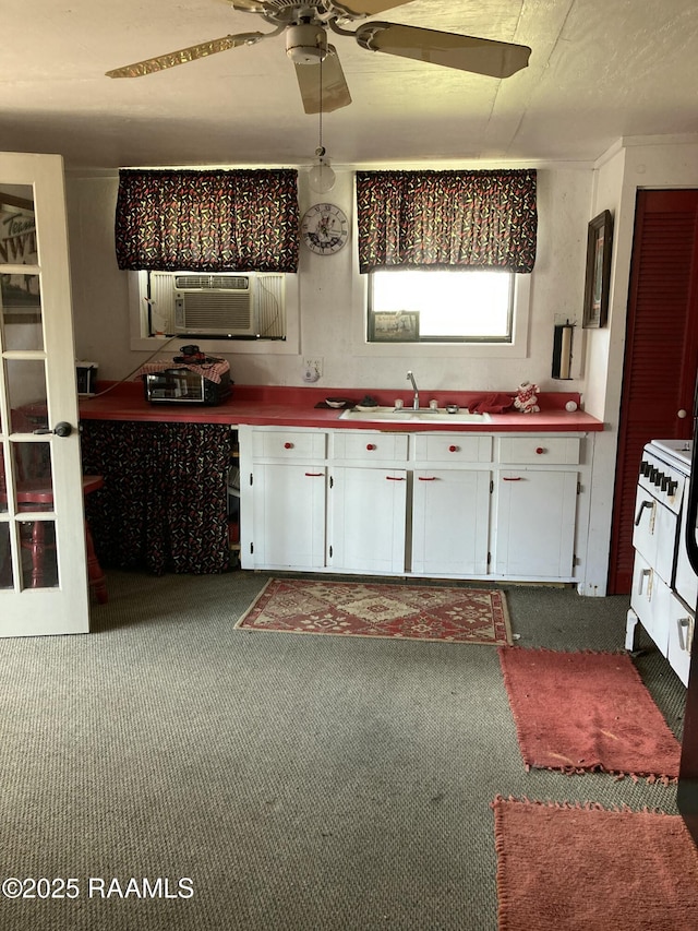 kitchen with carpet, white cabinetry, a sink, and white range