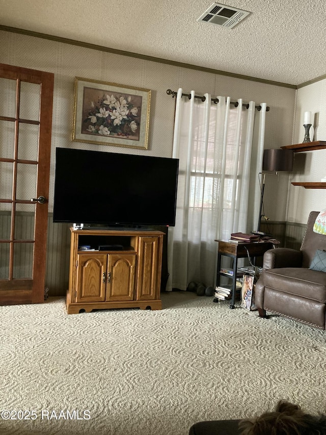 carpeted living room featuring visible vents, ornamental molding, and a textured ceiling