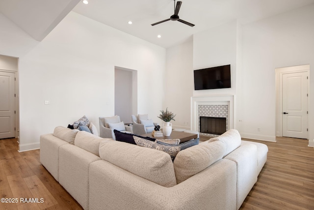 living area with baseboards, high vaulted ceiling, a fireplace, and light wood-style floors