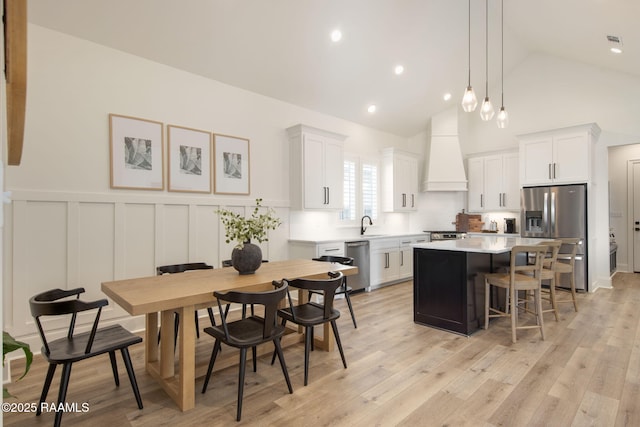 kitchen featuring a breakfast bar, light countertops, appliances with stainless steel finishes, custom exhaust hood, and a center island