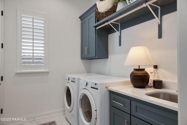 washroom featuring cabinet space, baseboards, marble finish floor, washing machine and dryer, and a sink