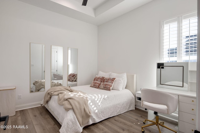 bedroom with ceiling fan, wood finished floors, and baseboards