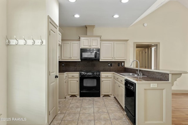 kitchen with dark countertops, black appliances, a peninsula, and a sink