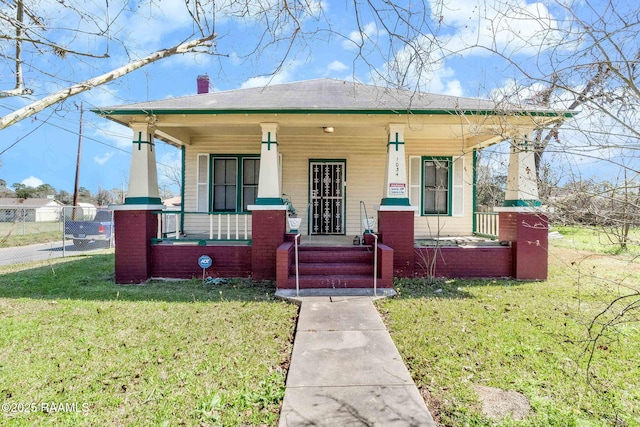 bungalow-style house with a porch, a front lawn, and a chimney