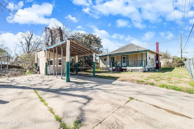 view of front of house with covered porch, driveway, fence, and a detached carport