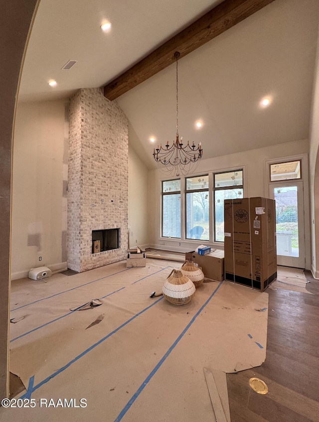 unfurnished living room with visible vents, beamed ceiling, an inviting chandelier, a fireplace, and high vaulted ceiling