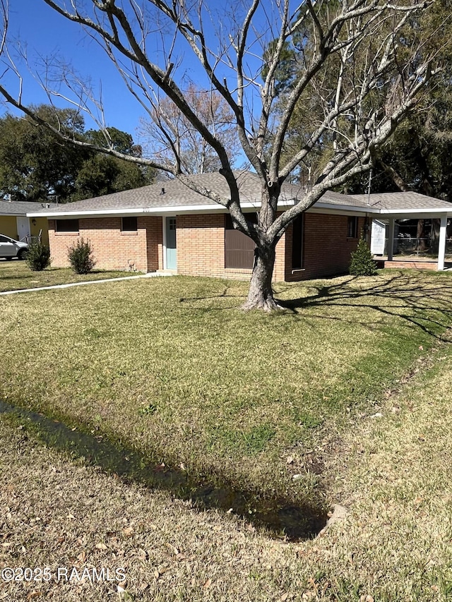 view of front of home featuring a front lawn, a carport, and brick siding