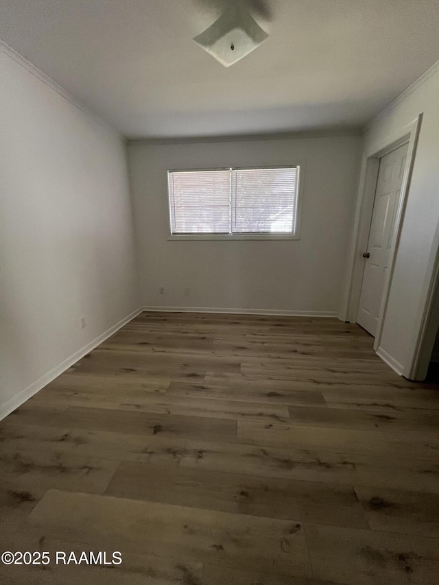 spare room with baseboards, wood finished floors, and ornamental molding