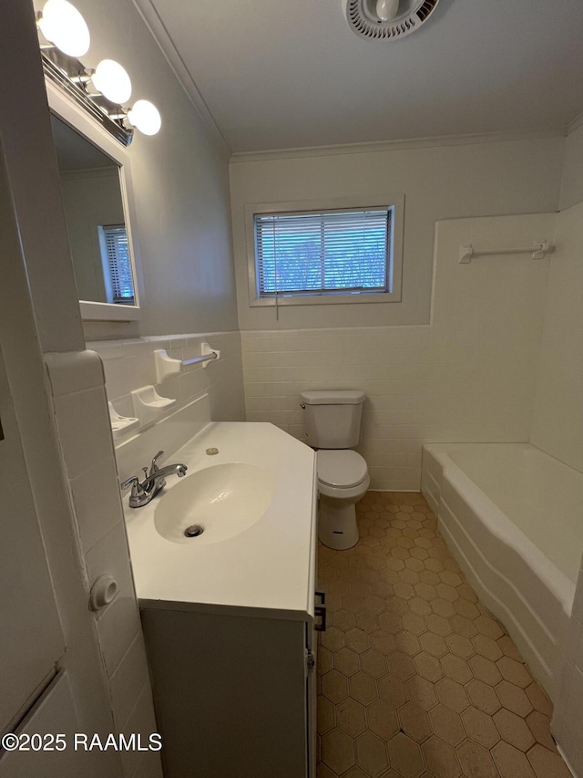 full bathroom with visible vents, toilet, crown molding, vanity, and tile walls