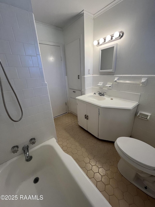 bathroom with toilet, vanity, tile walls, ornamental molding, and a tub