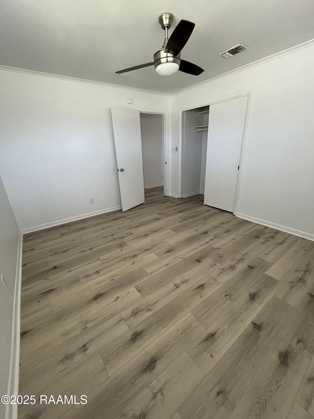 unfurnished bedroom with ornamental molding, a closet, visible vents, and wood finished floors