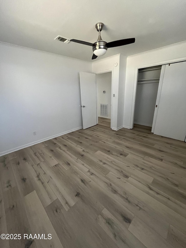 unfurnished bedroom with ceiling fan, a closet, visible vents, and wood finished floors