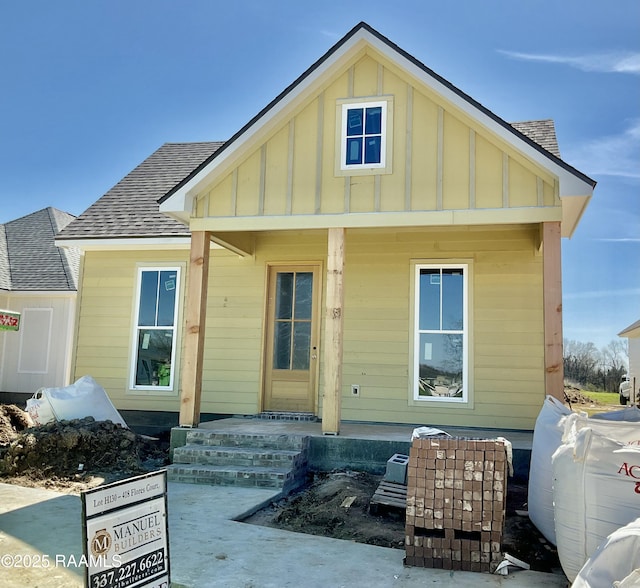 back of house with roof with shingles and board and batten siding