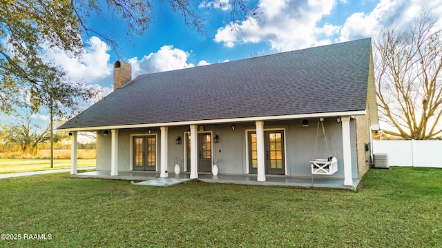 rear view of house featuring french doors, a yard, a chimney, central AC, and fence