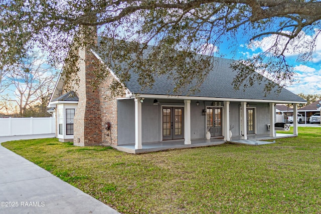 back of property with french doors, roof with shingles, a yard, a chimney, and fence