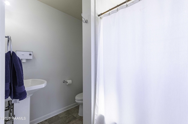 full bathroom with baseboards, a shower with shower curtain, and toilet