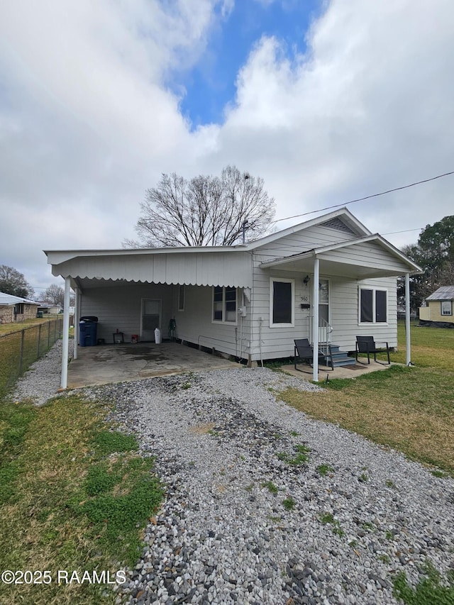 view of front facade with a carport, a front lawn, gravel driveway, and fence