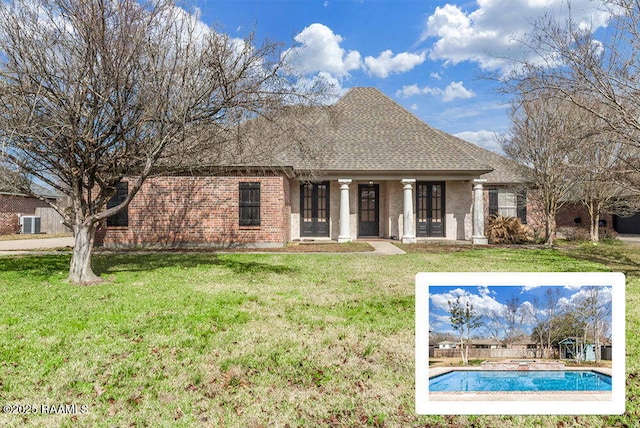 view of front facade featuring a front lawn, a shingled roof, brick siding, and a fenced in pool