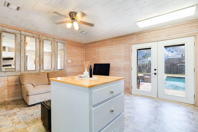 interior space featuring wood walls, visible vents, open floor plan, and french doors