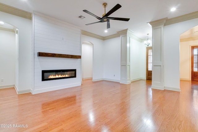 unfurnished living room with light wood finished floors, visible vents, a fireplace, and arched walkways