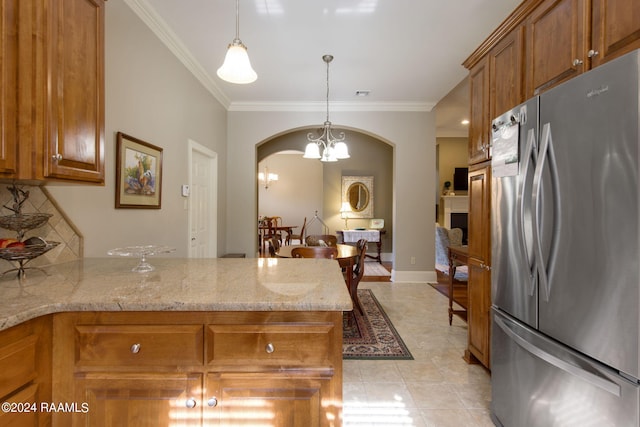 kitchen featuring a peninsula, ornamental molding, freestanding refrigerator, brown cabinets, and an inviting chandelier