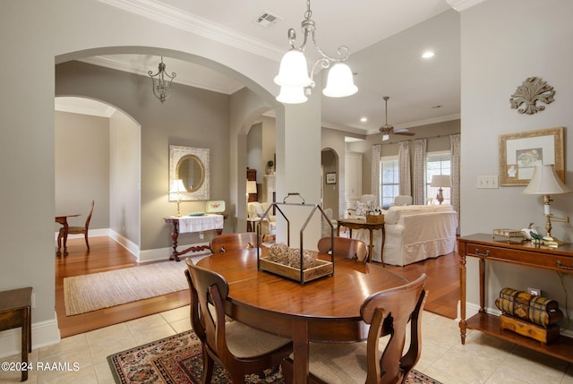 dining area featuring crown molding, light tile patterned floors, visible vents, baseboards, and ceiling fan with notable chandelier