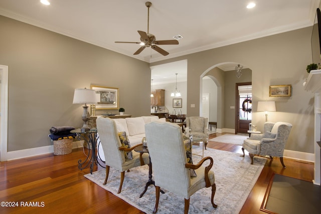 living area with arched walkways, light wood finished floors, baseboards, and crown molding