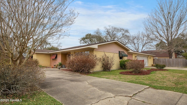 ranch-style home featuring an attached garage, brick siding, fence, concrete driveway, and a front lawn