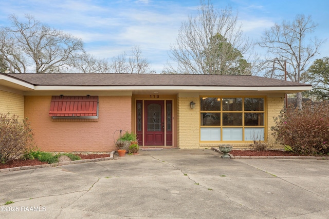 exterior space with brick siding and roof with shingles