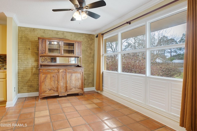 interior space featuring ornamental molding, ceiling fan, brick wall, and light tile patterned floors