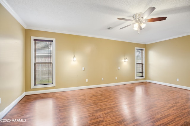 empty room featuring a textured ceiling, baseboards, wood finished floors, and crown molding