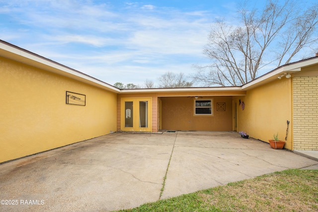 exterior space with a patio area, brick siding, and stucco siding