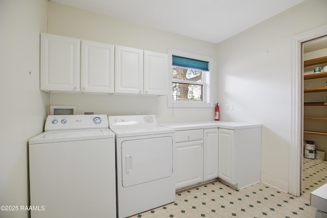 clothes washing area with light floors, washer and clothes dryer, and cabinet space