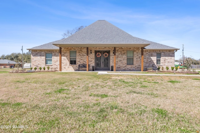 view of front of home featuring a shingled roof, a front lawn, french doors, and brick siding