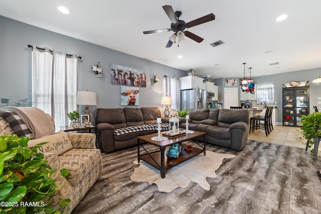 living area featuring light wood-type flooring, visible vents, ceiling fan, and recessed lighting