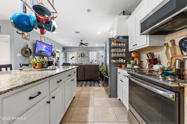 kitchen with light tile patterned floors, light stone counters, decorative backsplash, white cabinets, and appliances with stainless steel finishes