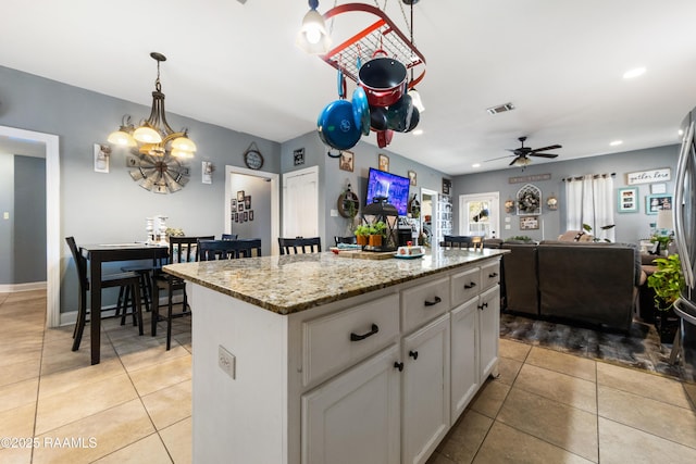 kitchen featuring white cabinets, light tile patterned floors, visible vents, and a center island