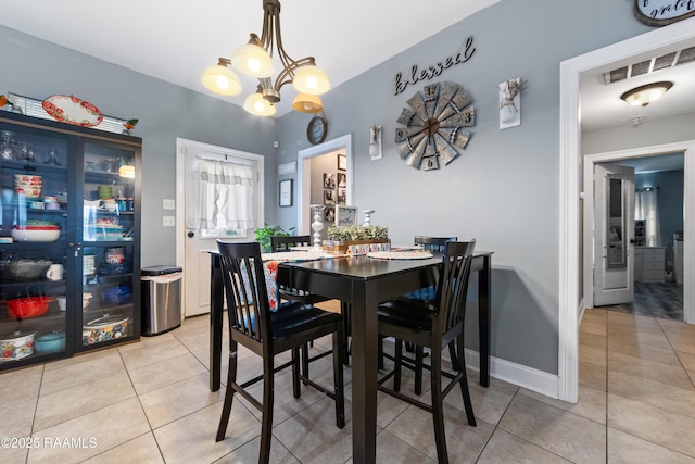 dining room featuring light tile patterned flooring, visible vents, baseboards, and a notable chandelier