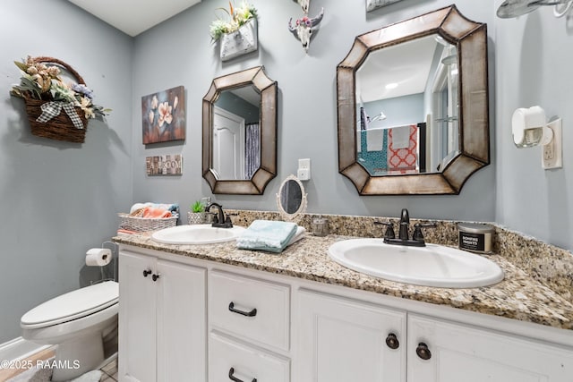 full bathroom with a sink, toilet, and double vanity