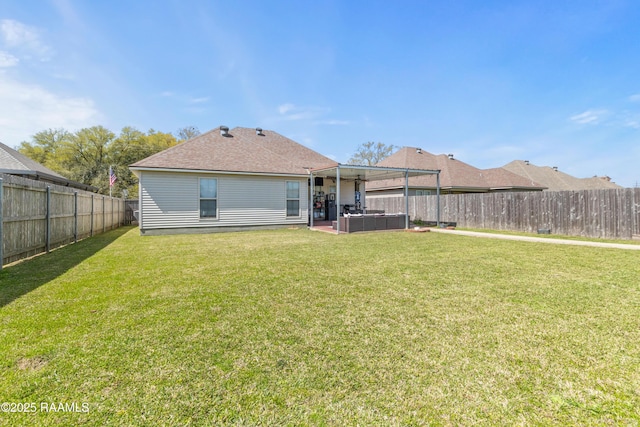 back of property featuring a yard, a hot tub, a fenced backyard, and a shingled roof