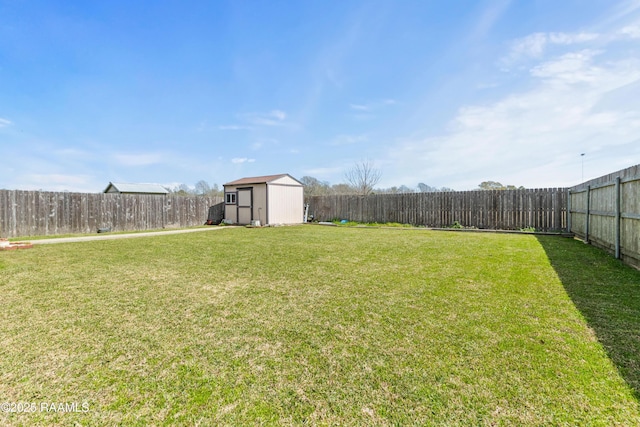 view of yard with an outbuilding, a fenced backyard, and a shed