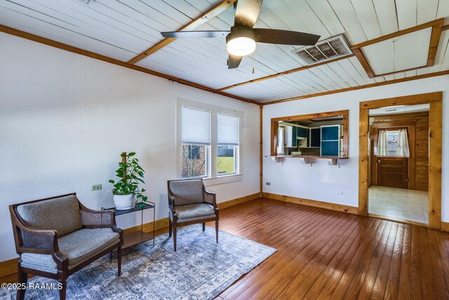 living area with visible vents, ornamental molding, baseboards, and wood-type flooring