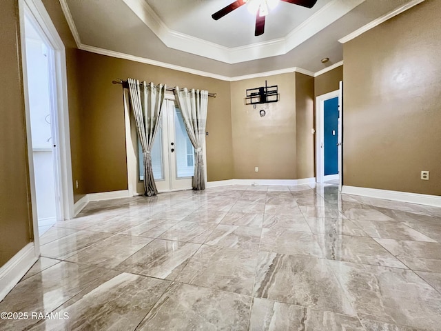 spare room with ornamental molding, a tray ceiling, and baseboards