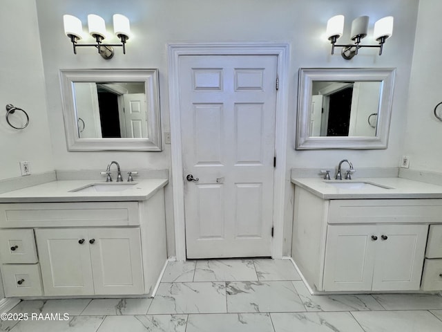 bathroom with marble finish floor, two vanities, and a sink