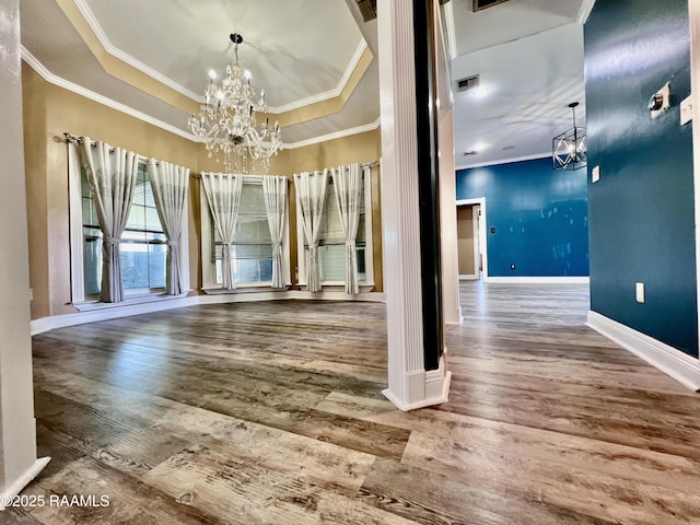 spare room featuring baseboards, a raised ceiling, a notable chandelier, and wood finished floors