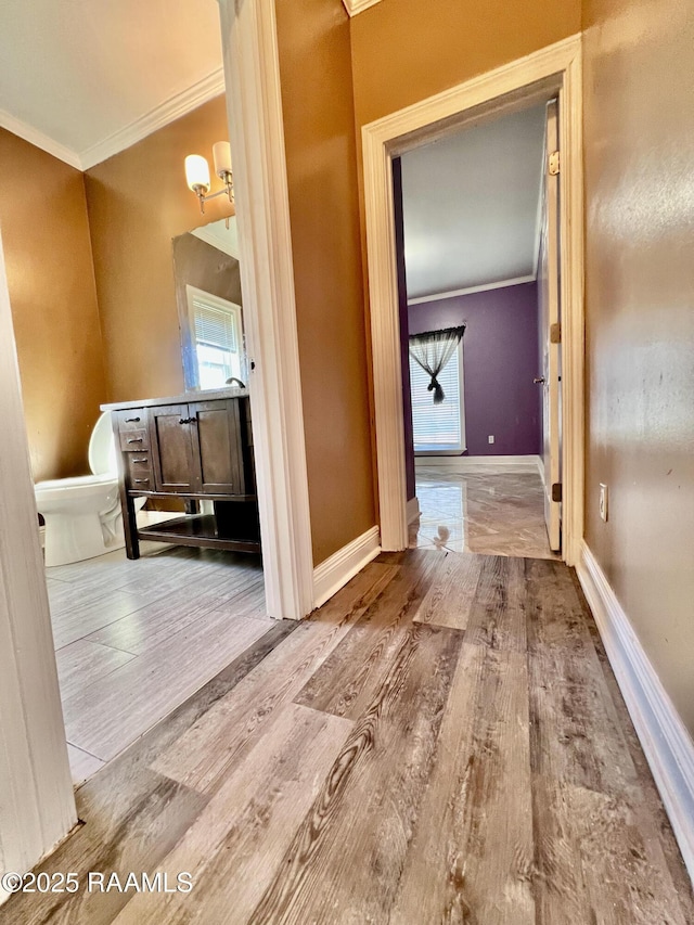 bathroom featuring toilet, crown molding, baseboards, and wood finished floors