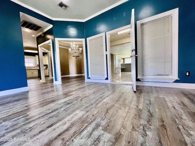 unfurnished bedroom with visible vents, crown molding, baseboards, and wood finished floors