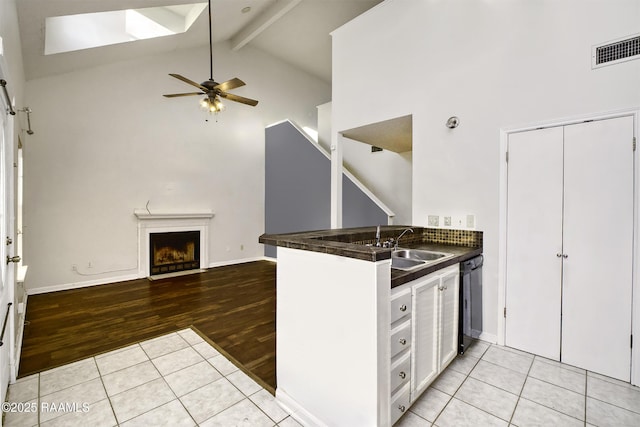 kitchen with visible vents, dark countertops, open floor plan, a fireplace, and beam ceiling