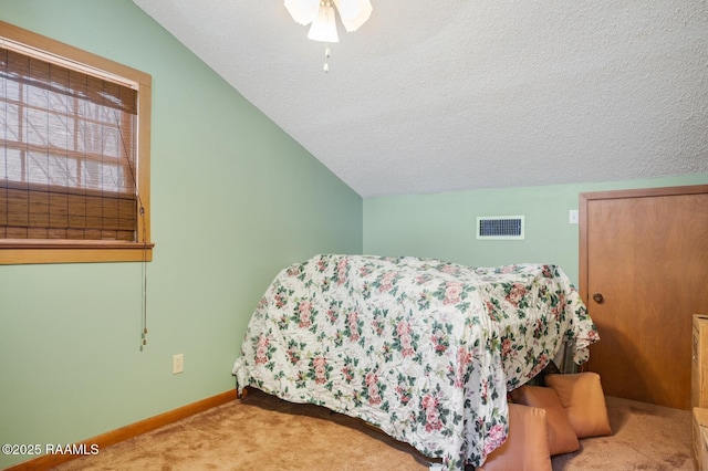 carpeted bedroom featuring lofted ceiling, visible vents, a textured ceiling, and baseboards